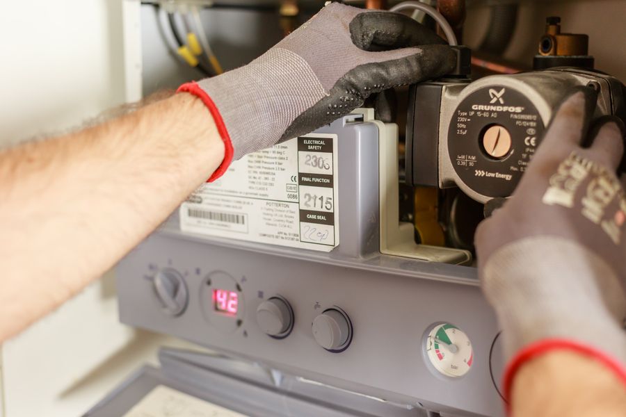 Gloved hands servicing a furnace circulation pump and control board