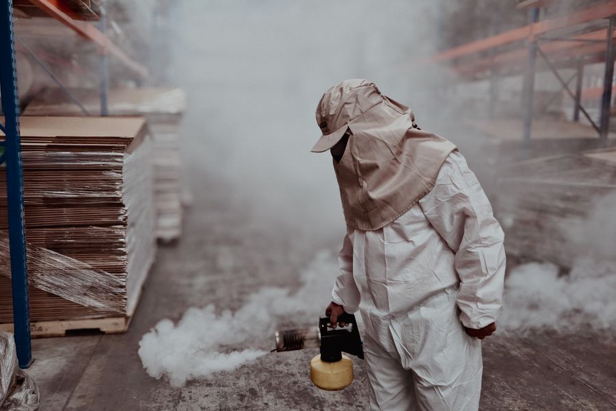 Pest control professional in protective gear fogging a warehouse