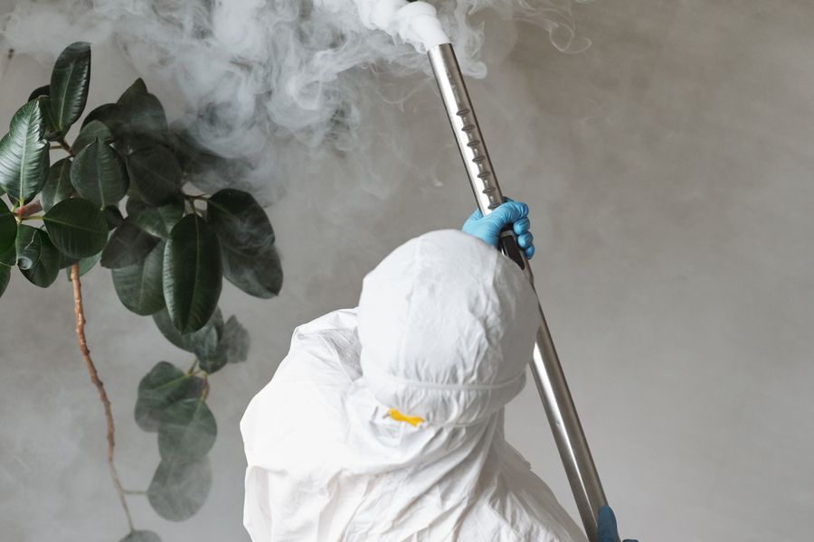 Technician in protective suit fogging the interior of a property