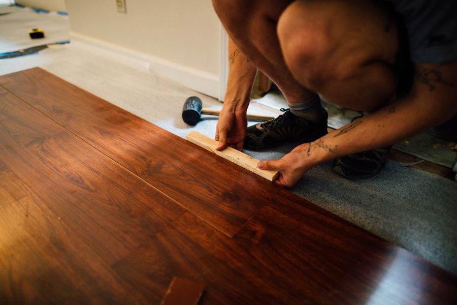 Installer tapping hardwood flooring planks into place