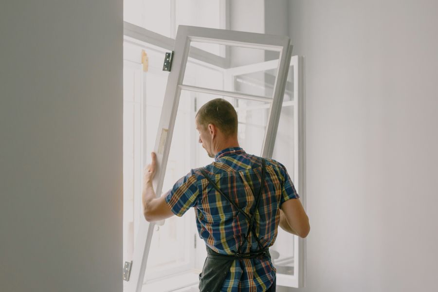 Installer carrying a new window sash to the opening