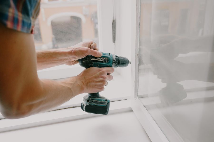 Installer drilling into a window frame during fitting