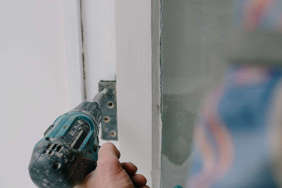 Close-up of a drill fastening window hardware to the frame